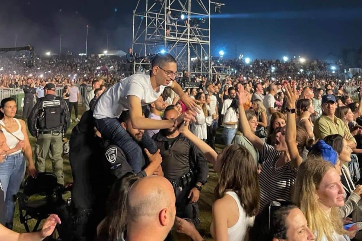un policier prend un handicapé sur ses épaules dans un concert