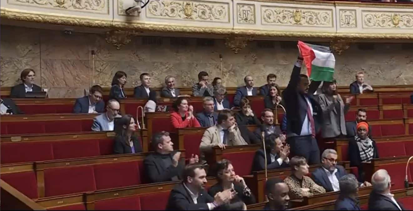 Image illustration un député LFI brandit un drapeau Palestinien pendant une séance à l'assemblée.