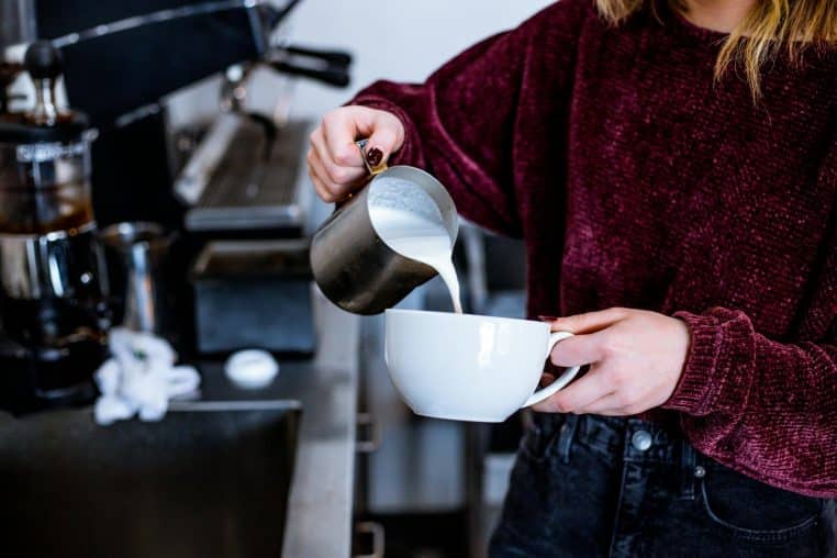 Woman Pouring Milk on Cup