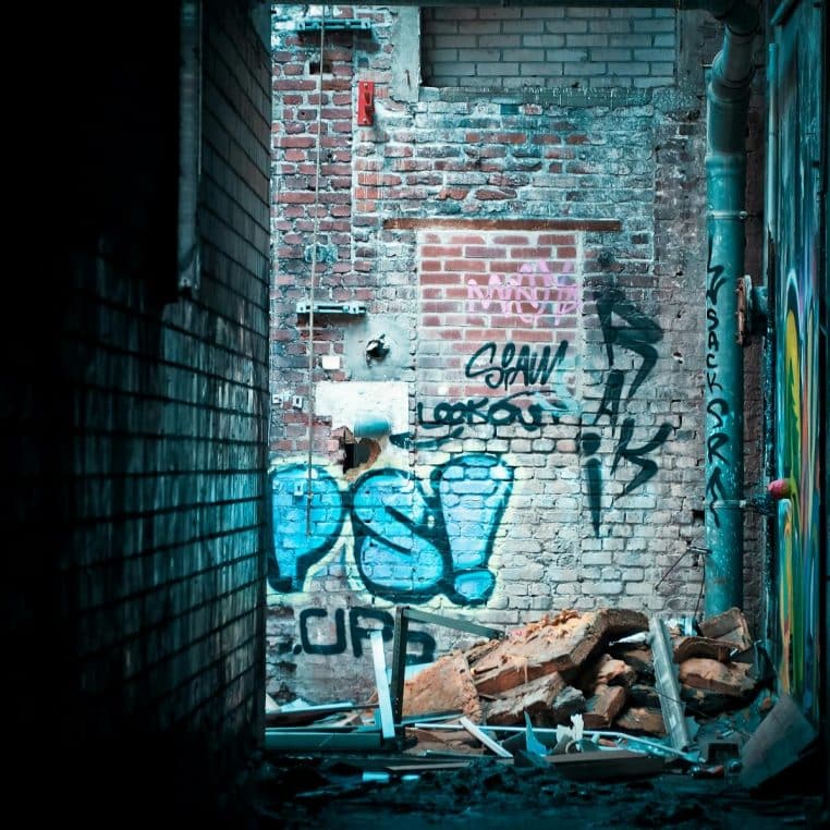 Abandoned alley showcasing vibrant graffiti on a dilapidated brick wall.