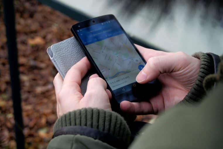 Close-up of hands using a map app on a smartphone outdoors, showcasing GPS navigation.