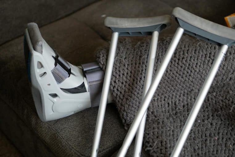 Close-up of an orthopedic boot and crutches on a couch, symbolizing injury recovery at home.