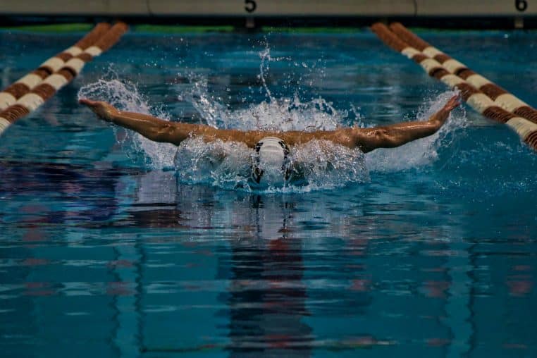 a man swimming in a pool with a swimming board