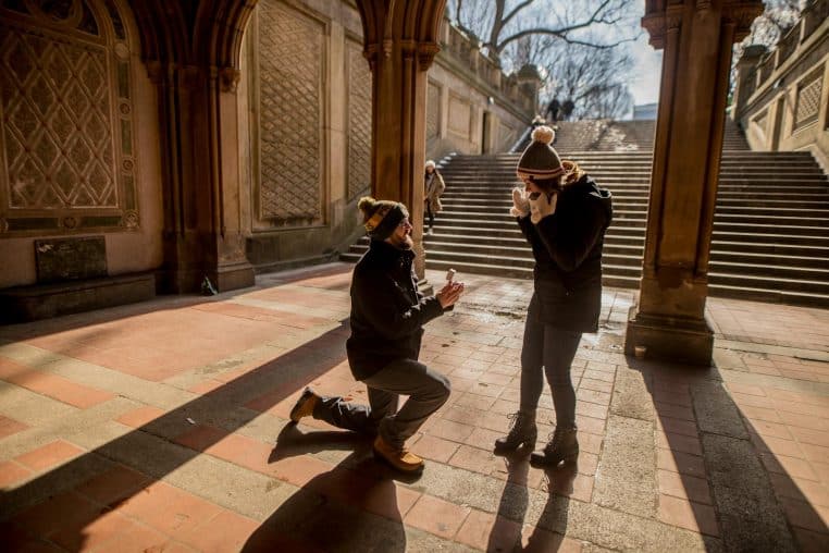 A couple shares a marriage proposal moment under Bethesda Terrace, Central Park.