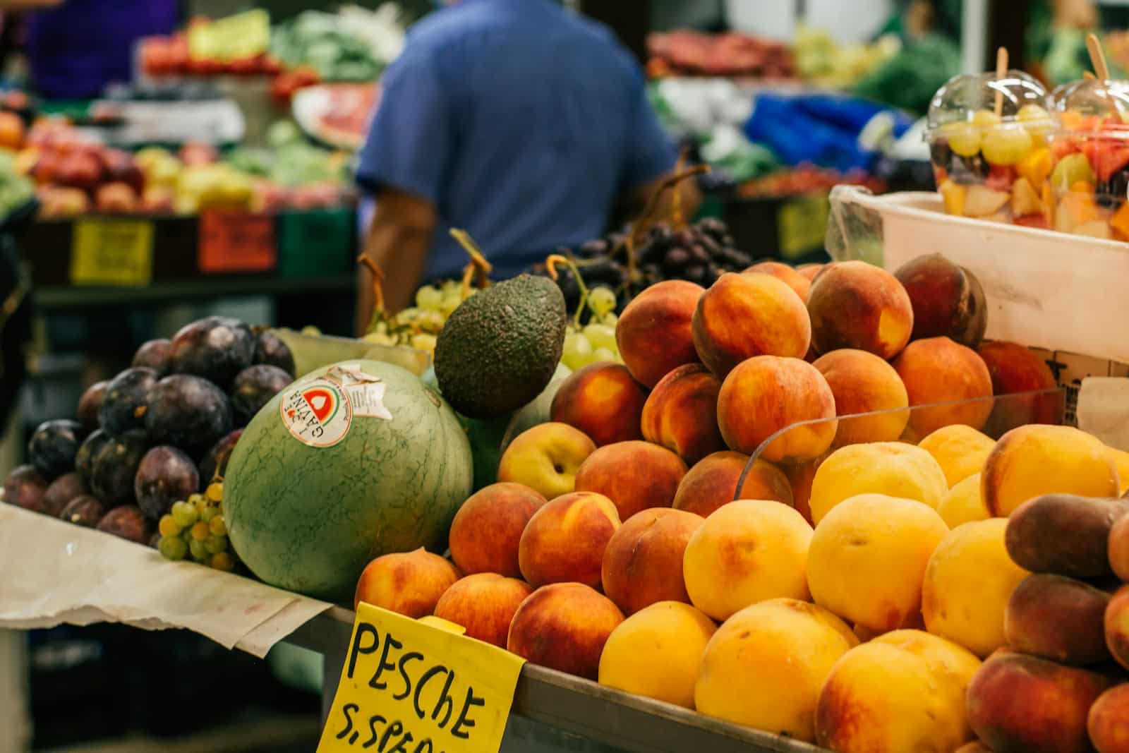 man in blue shirt standing near fruit stand